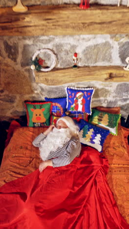santa claus is sleeping in specially decorated room in his bed. he is holding his hand under his cheek. christmas spirit concept close up video. vertical video
