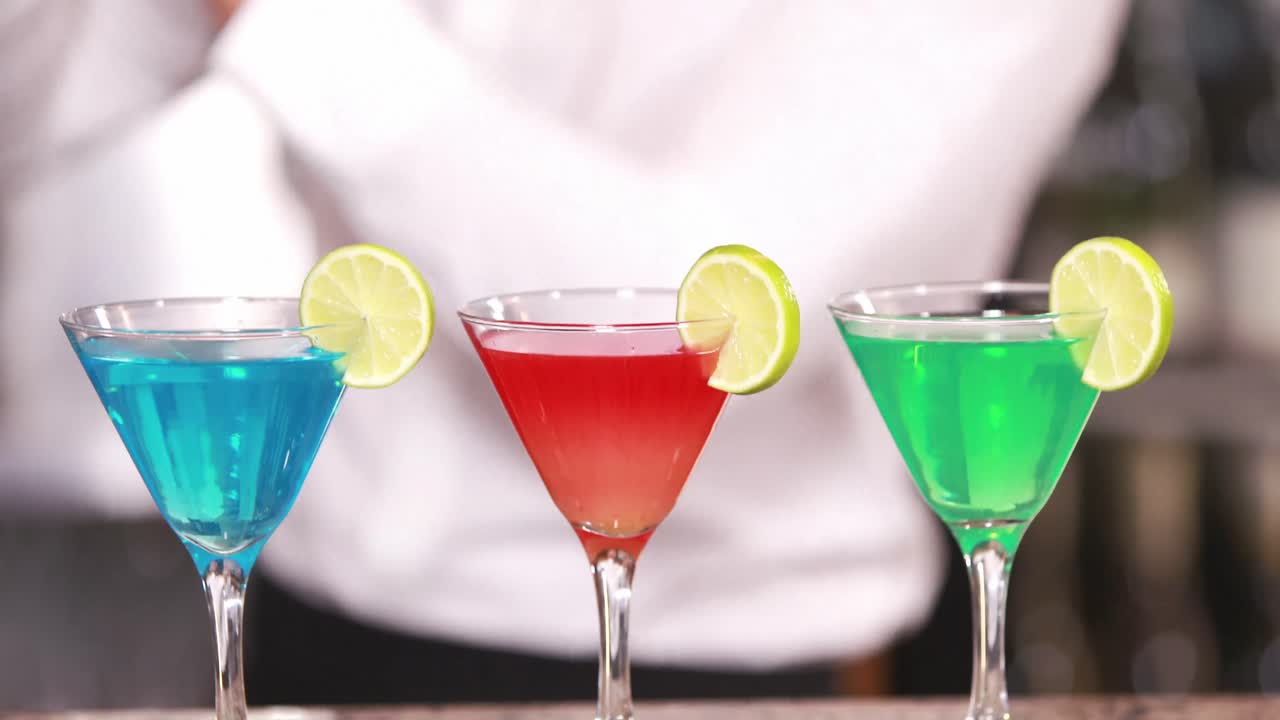 barman sonriente sirviendo cócteles de colores