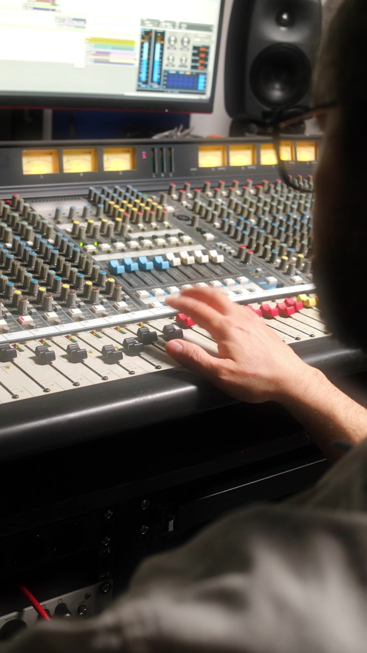 Sound Engineer Operating Mixing Desk at Work in Recording Studio