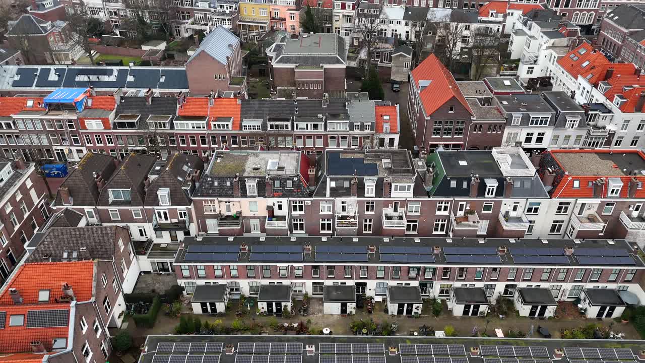 Dense townhouses with solar panels on roof in dutch neighborhood. Aerial birds eye shot. Winter day in The Hague Town. Black and orange rooftops.
