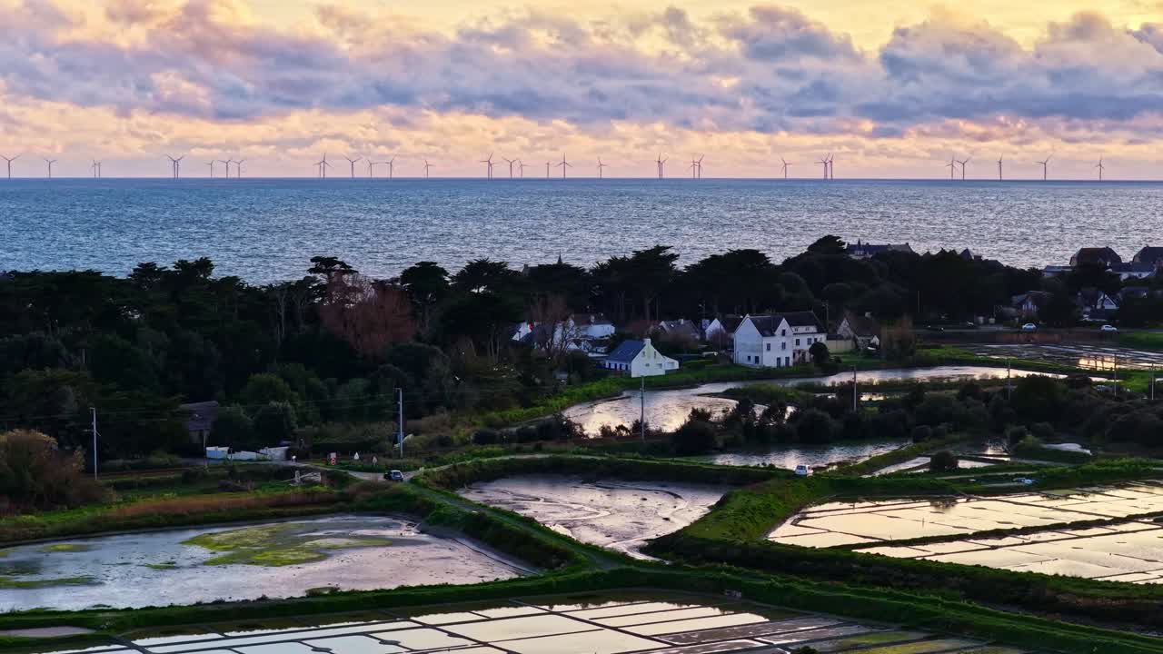 Una vista aerea al crepuscolo del villaggio costiero di Le Croisic, saline allagate e un parco eolico offshore distante. Francia