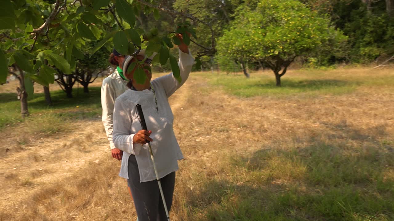 맹인 여성이 광야를 탐험하는 데 도움을 주는 가이드와 함께 자연 지역을 지팡이를 짚고 걷는다 5