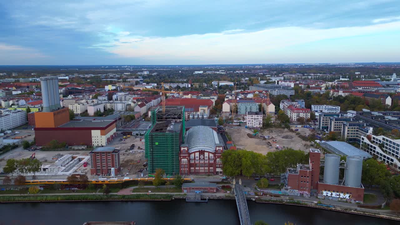 Combined heat and power plant operating in the cityscape by Spree river with new buildings under construction. Magic aerial view flight fly reverse drone