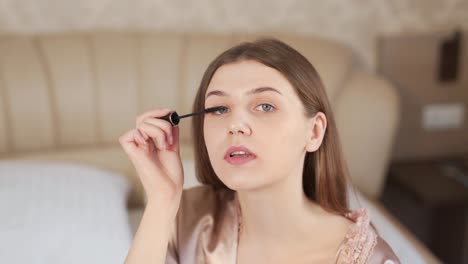 portrait of a pretty woman drawing eyelashes with mascara