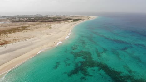 aerial view over beautiful blue turquoise ocean waters beside idyllic beach