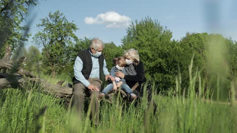 grandparents with granddaughter in medical masks in park. coronavirus quarantine