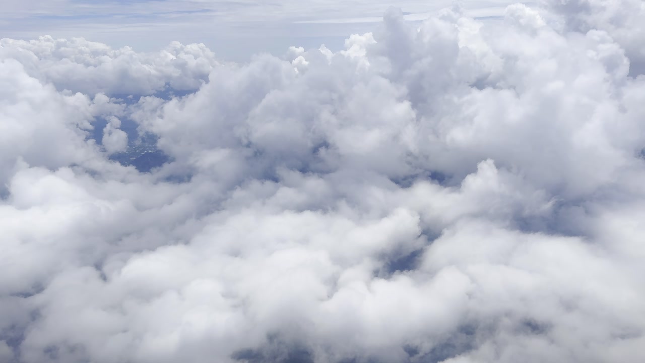 Footage of white clouds and sky in motion, captured from an airplane. Perfect for travel, aerial views, and nature projects, showcasing serene skies and dynamic movement above the landscape
