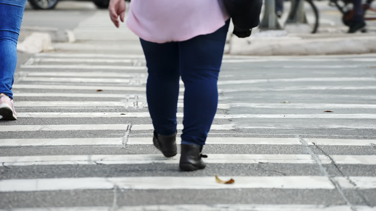 People crossing a street by the crosswalk of a big city in daylight filmed in slow motion in 4K high definition