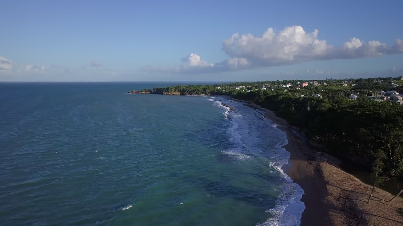 antena, volando sobre una bahía poco profunda con una playa de arena cerca de un pueblo