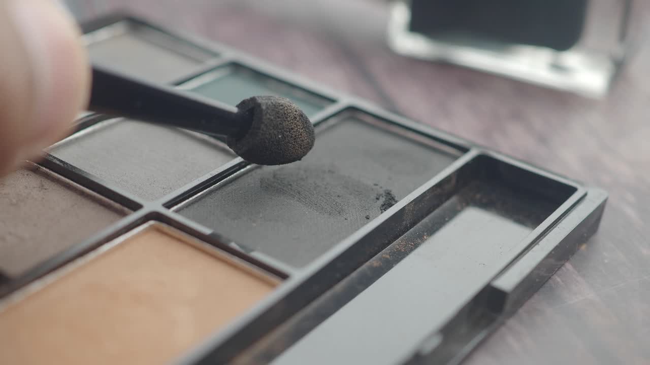 Close Up of Hand Applying Black Eyeshadow from Palette