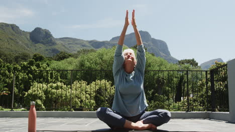 practicing yoga, senior woman on balcony with peaceful mountain view backdrop, copy space