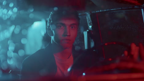 portrait of young man behind steering wheel in car at night