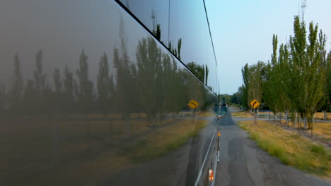 side view of a public bus, shuttle, or school bus driving and the road reflection on it