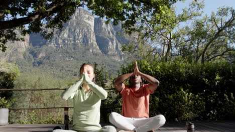 happy diverse couple practicing yoga meditation sitting in sunny nature, copy space, slow motion