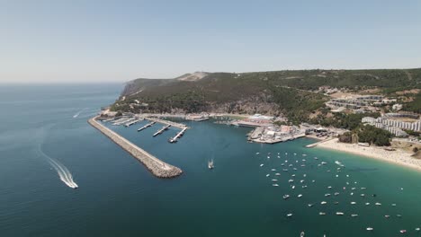 aerial pullback reveal natural landscape, sesimbra coastline with marina and beautiful beach shore