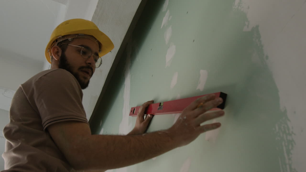 Construction worker using level on drywall