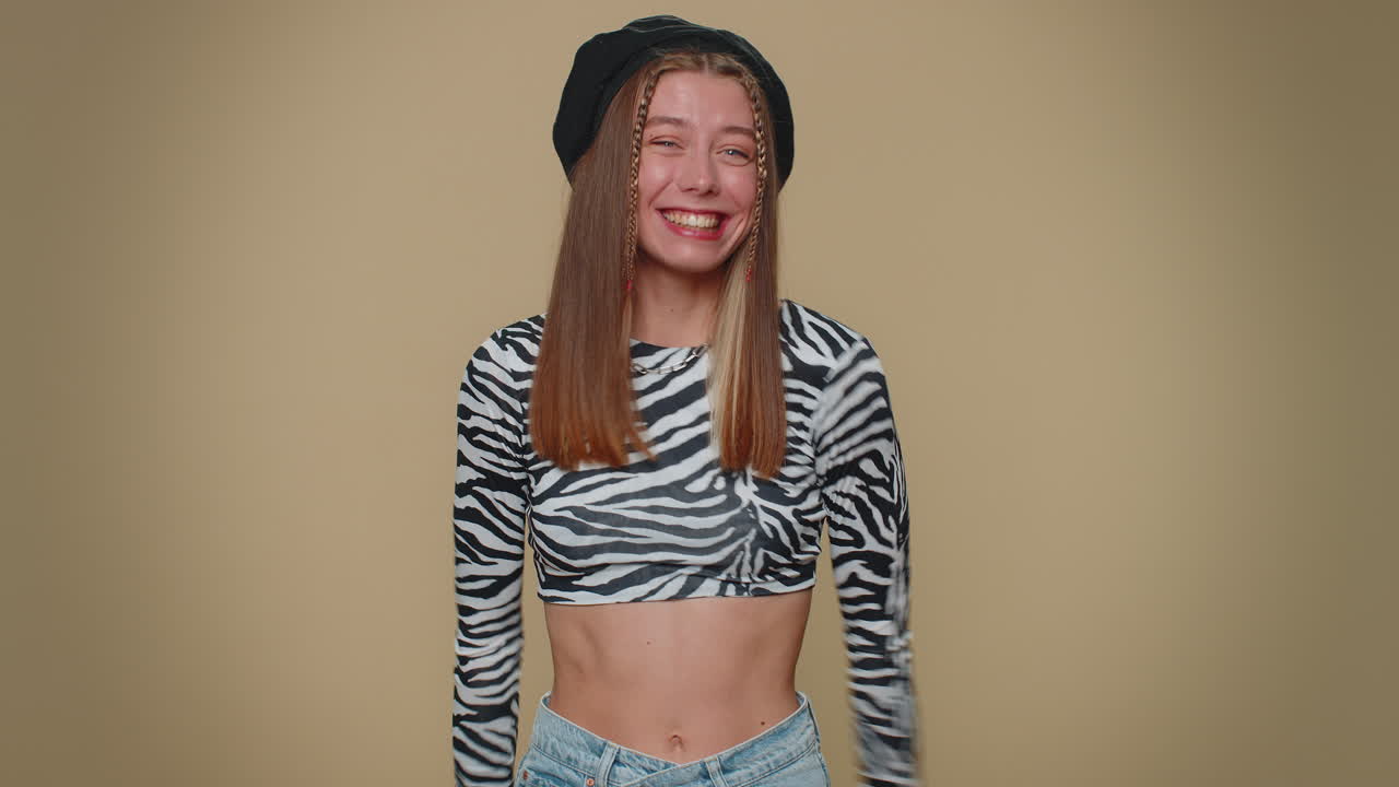 una hermosa mujer aparece desde abajo saludando con la palma de la mano, saludando con una hospitalaria sonrisa amistosa