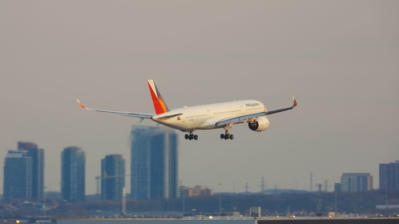 Philippine airlines airbus a350 modern passenger airplane approaching airport runway, flying over urban skyline during landing in Toronto, Canada