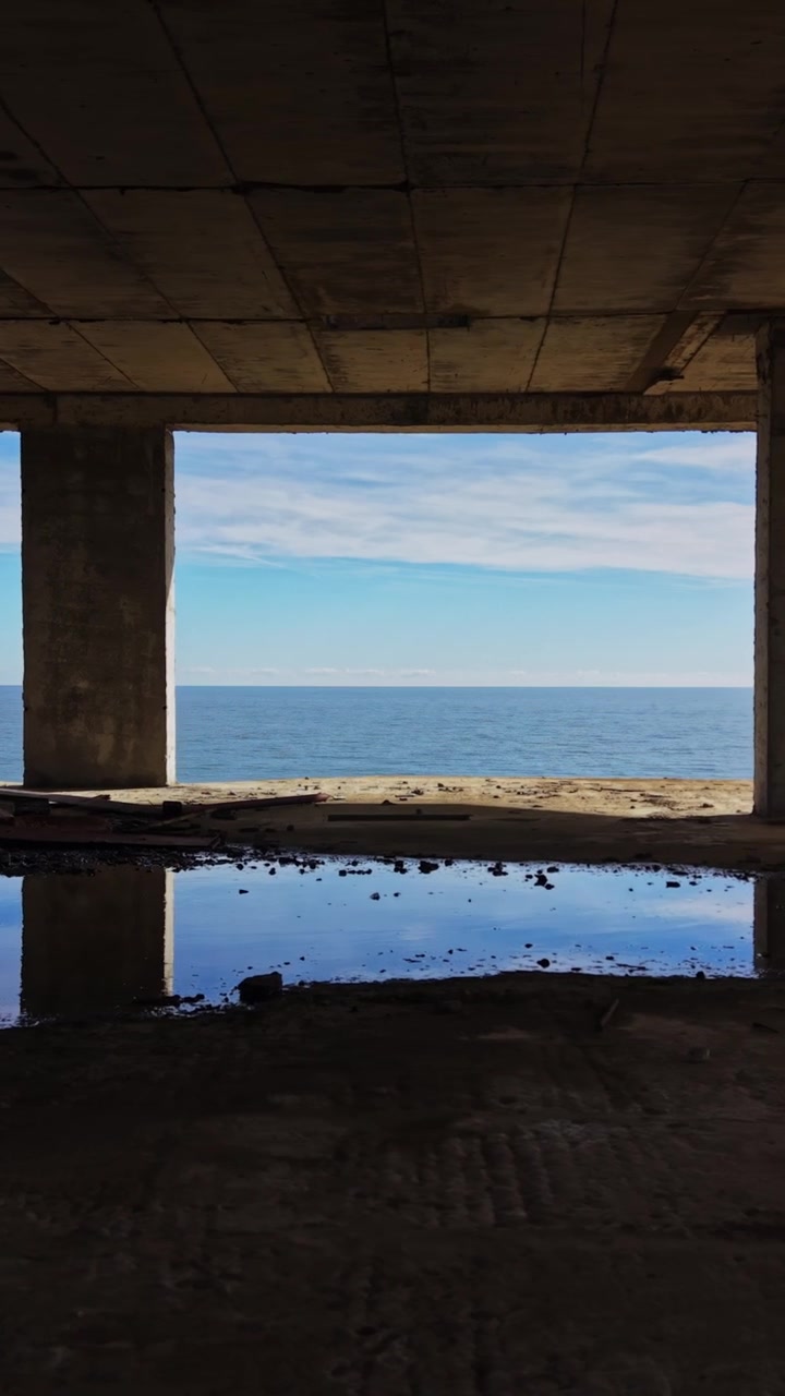 View of ocean through concrete pillars at an empty coastal site