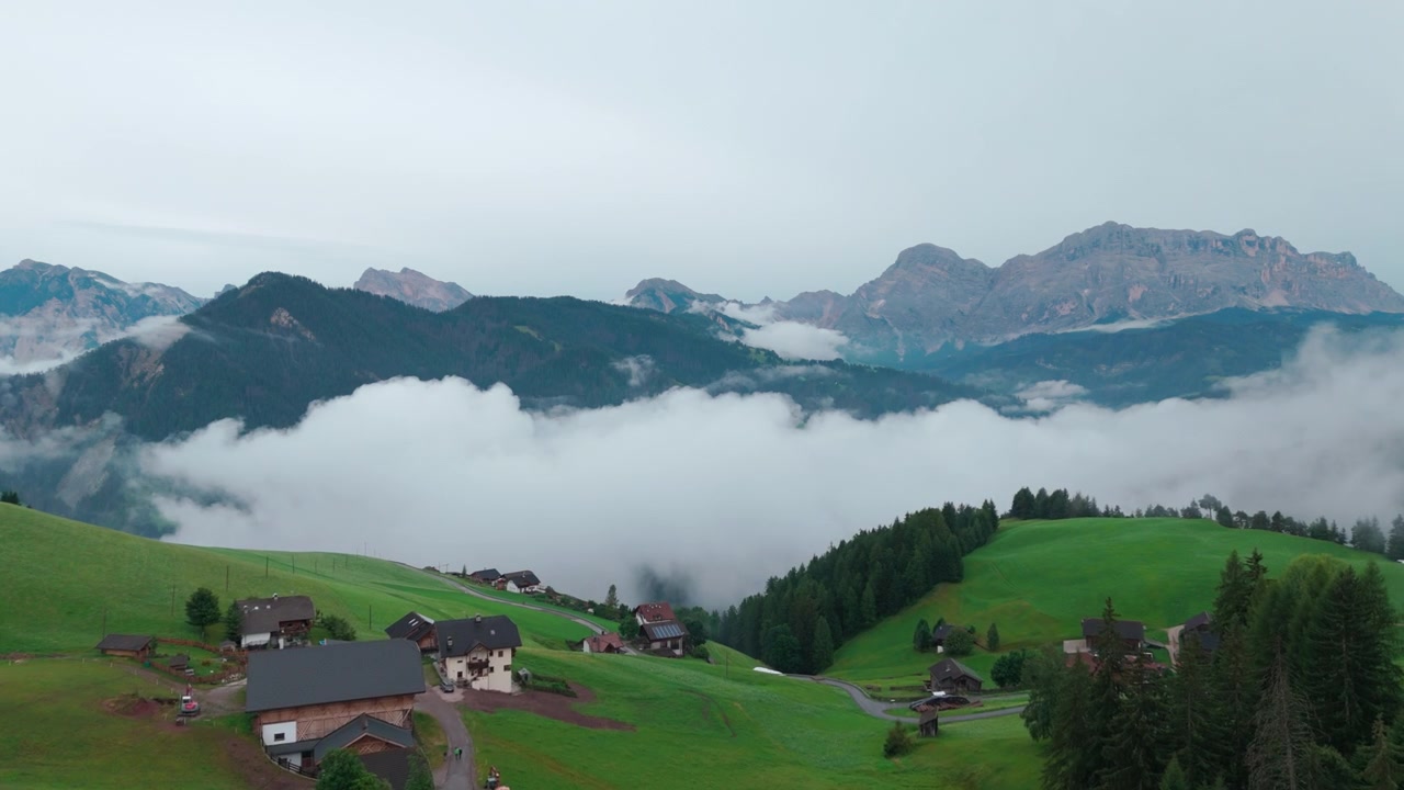 Una vista aerea in una giornata nuvolosa di una valle lussureggiante vicino a Ortisei, Italia, che mostra paesaggi sereni.
