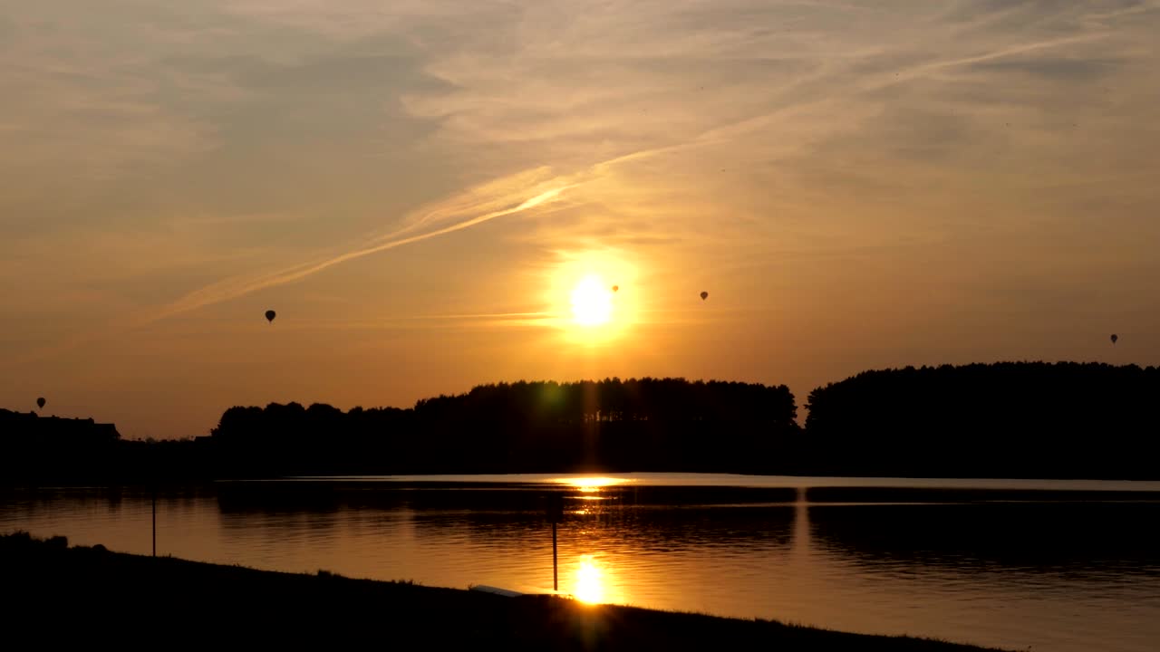해가 지고 호수가 있는 배경에 있는 풍선