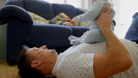 father playing with his baby boy in living room 4k