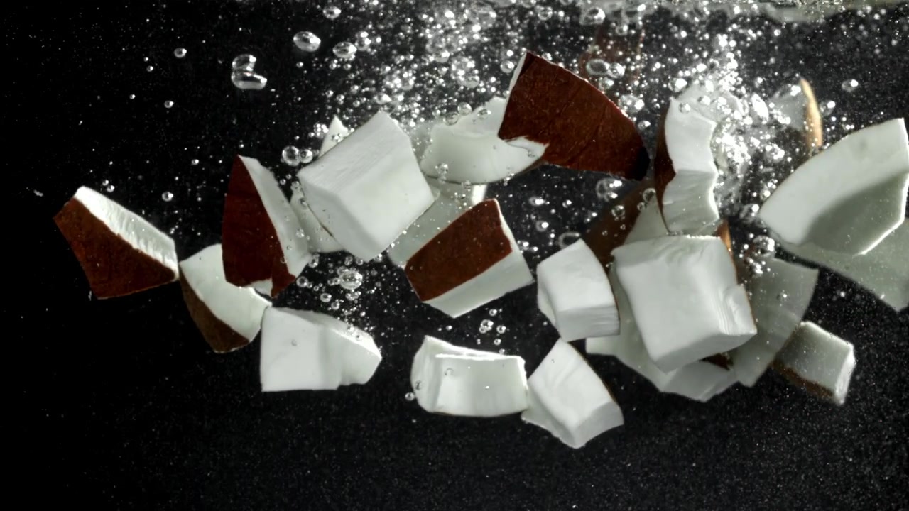 Fresh Coconut Pieces Splashing into Water in Slow Motion