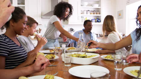 dos familias con niños adolescentes comiendo comida en la cocina
