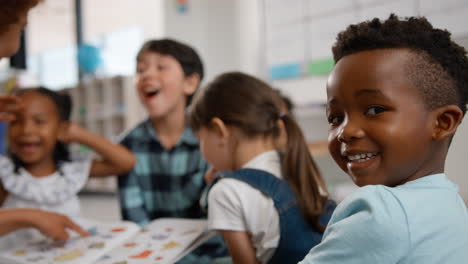 portrait of male elementary school pupil with teacher reading to class in background