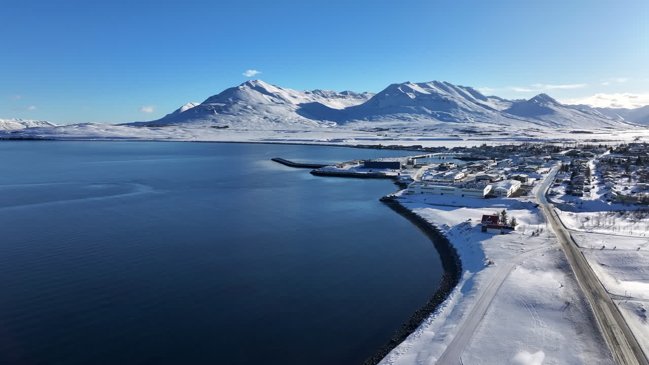 Idyllic winter wonderland village along a pristine lake, snow covered mountains in background, aerial