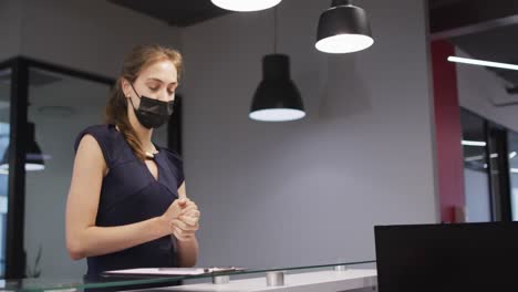 Kaukasische-Frau-Mit-Gesichtsmaske-Desinfiziert-Hände-Und-Meldet-Sich-An-Der-Rezeption-Des-Büros-An