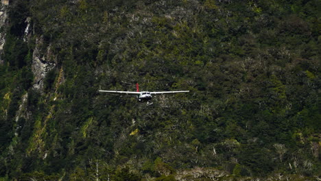 plane flies over the mountain in milford sound and lands on airstrip