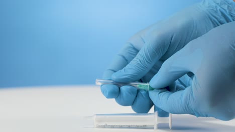 Medical-practice-assistant-prepares-syringe-needle-with-blue-gloves,-background