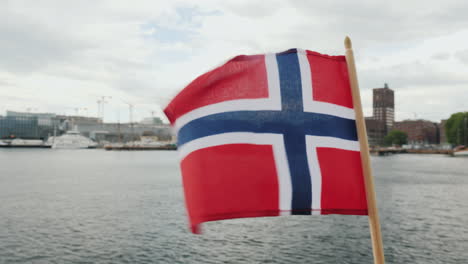 walking with the flag of norway against the background of the city line of oslo steadicam shot