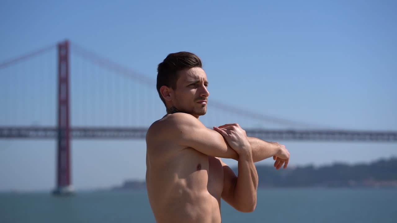 셔츠 없는 근육이 있는 남자가 야외에서 팔을 펴고 있습니다.