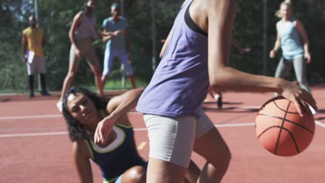 Happy-diverse-female-basketball-team-training-with-male-coach-on-sunny-court,-in-slow-motion