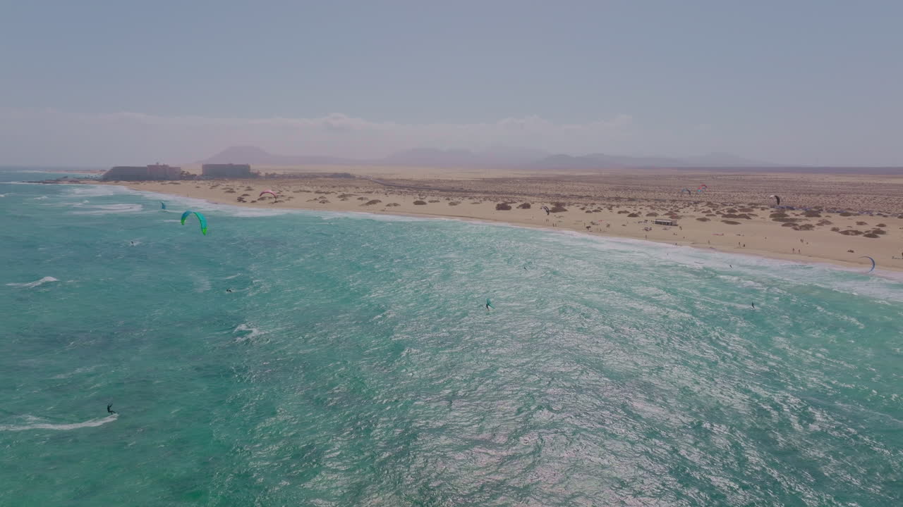 Breathtaking views of Fuerteventura with Lobos Island, Red Flag Beach, kite surfers, sunsets, volcanoes, sand dunes, and wingfoilers in the Canary Islands’ golden light.