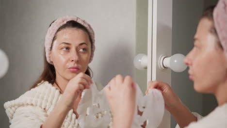 woman applying face cream in bathroom