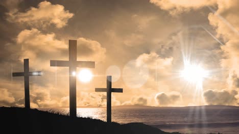 animation of three christian crosses over landscape with sun glowing on orange sky