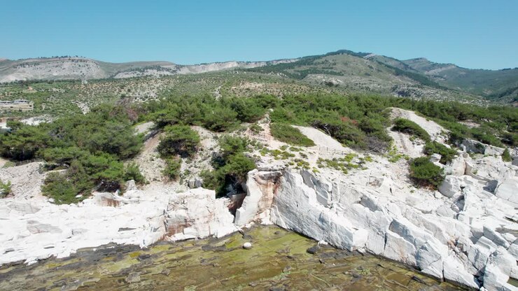 Aerial View Of A Massive Marble Wall In Aliki Ancient Marble Quarry With High Mountain Peaks In The Background And The Mediterranean Sea In The Foreground, Vivid Colors, Thassos Island, Greece
