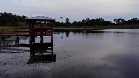 Drone-view-pushing-in-a-body-of-water-pond-with-a-small-dock-in-water-brackish-water