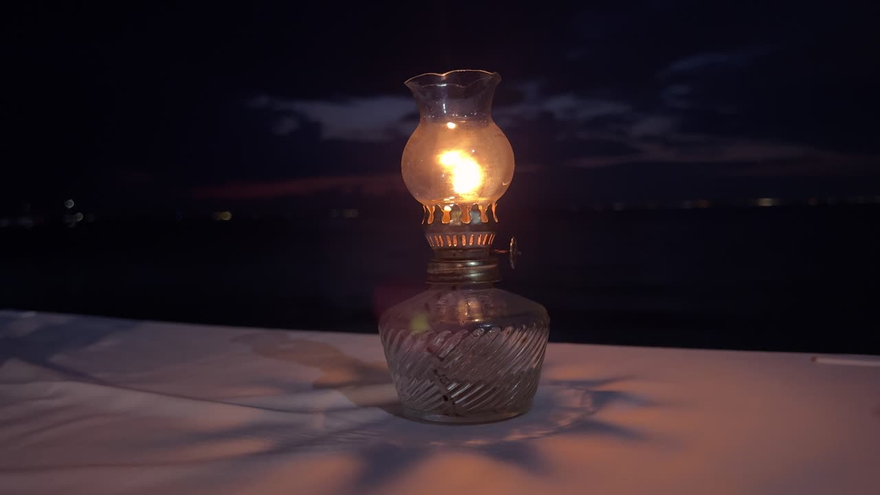 빈티지 오일 램프에서  ⁇ 박이는 불꽃은 어두운 배경에 테이블에 그림자를 던집니다.