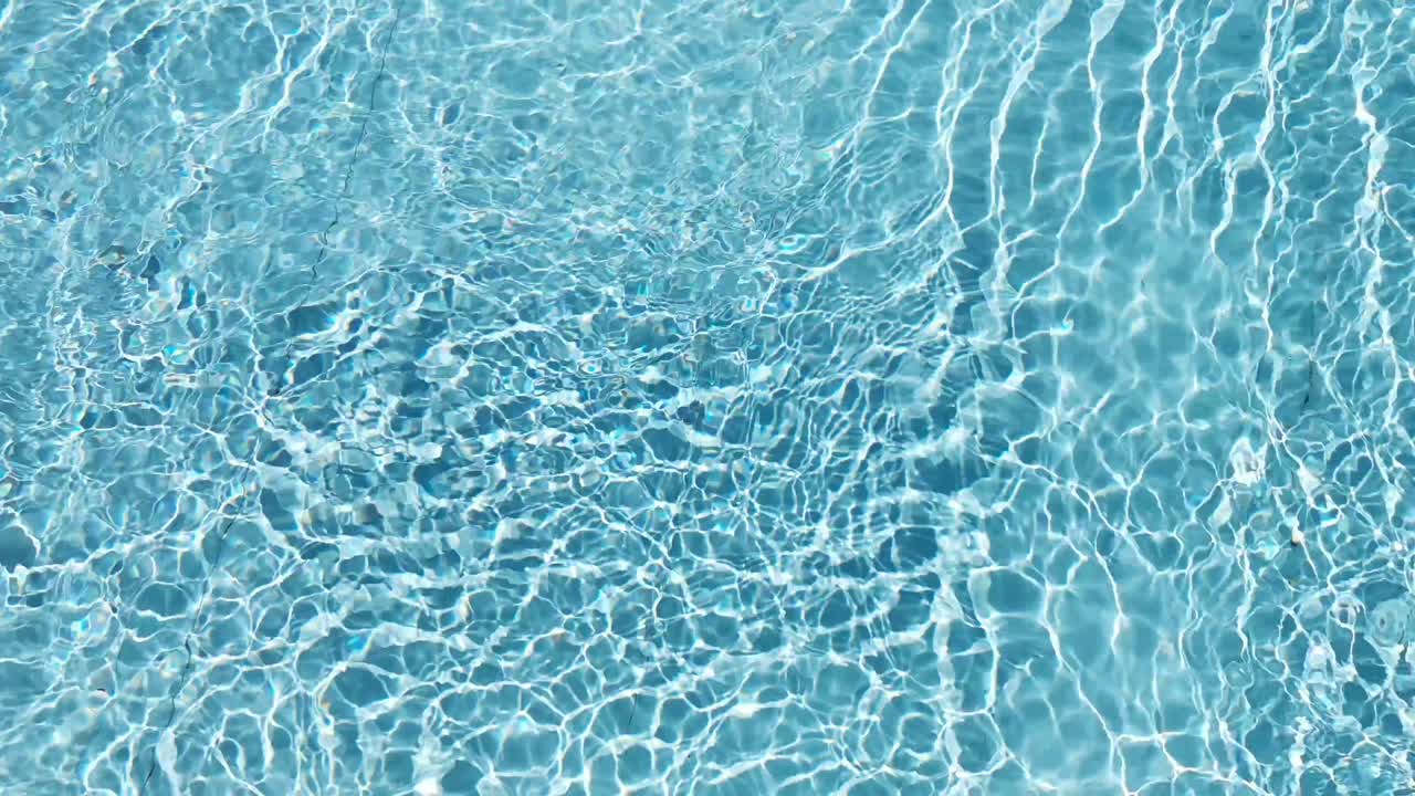 Tekstur permukaan air, riak dan gelombang kolam renang bersih gerak lambat, refraksi sinar matahari pada tekstur pasir putih tepi laut dari pandangan atas, latar belakang air yang disinari matahari. Latar Belakang Kaustik Air.