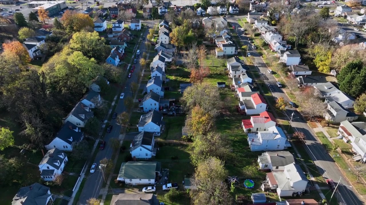 Case e abitazioni lungo un viale alberato colorato in autunno. Strada dritta in un idilliaco quartiere suburbano degli USA. Ripresa dall'alto con drone in discesa. Case unifamiliari in Virginia