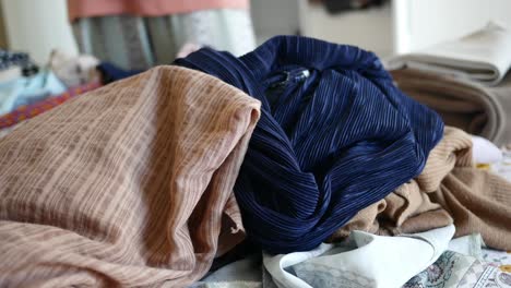 close-up of a pile of folded fabrics, featuring a blue pleated fabric and a brown patterned fabric.