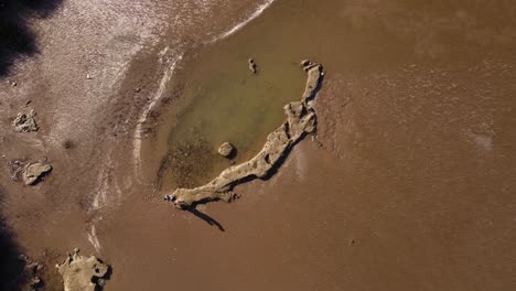 Two-Friends-Walking-On-Rocks-On-Rio-De-La-Plata-River,-Buenos-Aires