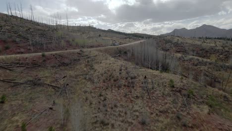 Aerial-view-of-a-vehicle-driving-along-a-remote-mountain-road-in-the-Pike-National-Forest,-Rocky-Mountains,-Colorado