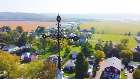 Orbital-drone-shot-of-a-neighborhood-and-nearby-farmlands-located-in-Montréal,-in-Québec,-Canada-during-fall-season