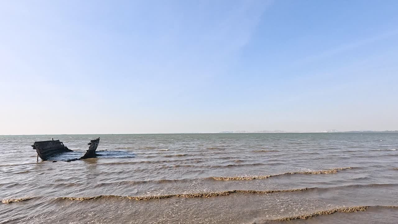파도 들 이 해변 에 있는 부서진 배 를 둘러싸고 있다