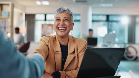 businesswoman shaking hands with a colleague in an office setting.